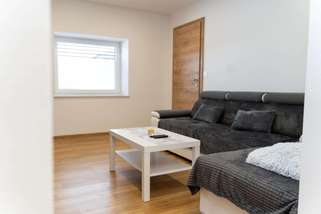 Svetla dnevna soba apartmaja v Oplotnici s sedežno garnituro in oknom
