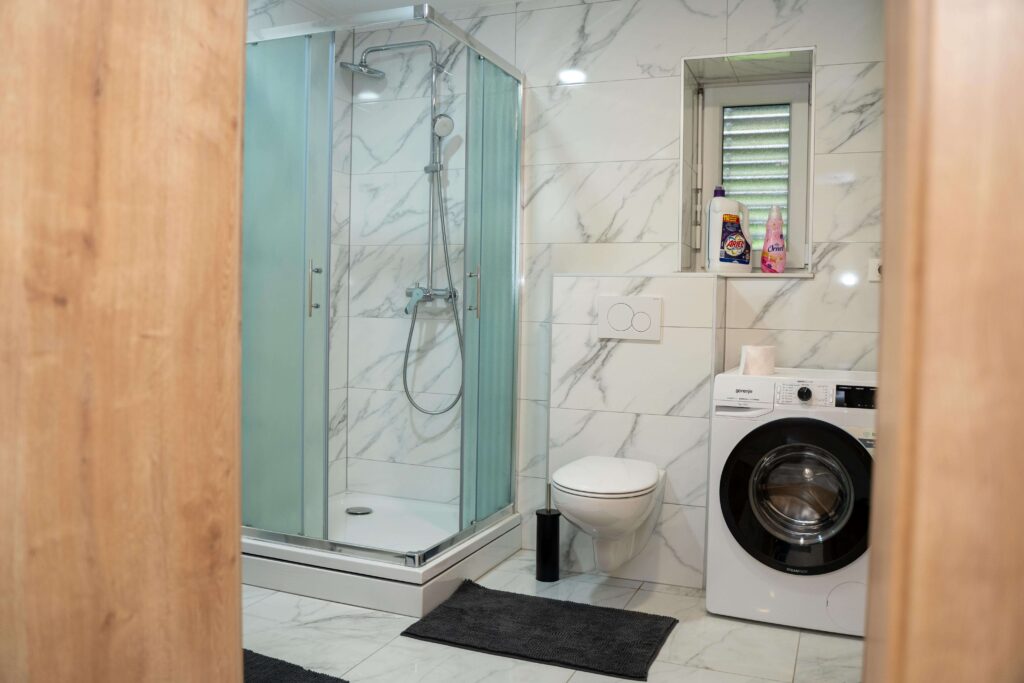 Kopalnica apartmaja v Oplotnici s tušem, WC-jem in pralnim strojem – Edi Residence